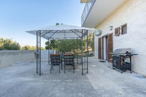 a table and chairs under an umbrella next to a grill at Melissa apartments in Halikounas