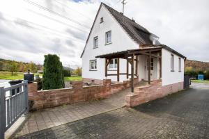 a small white house with a brick wall at Ferienwohnung Nickel in Hofstetten