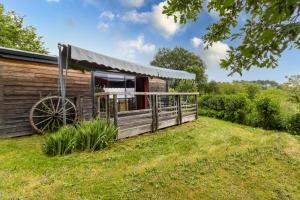 a log cabin with a large porch and a large wheel at Tiny House, Clim et Bassin in Auriac-du-Périgord