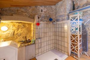 a bathroom with a shower in a stone wall at Villa L'Elzède in Les Vans +17 photos