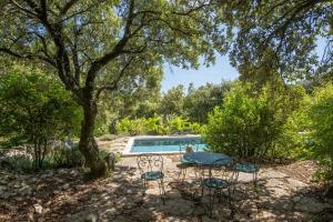 a pool with two chairs under a tree at Villa L'Elzède in Les Vans