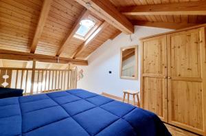 a bedroom with a blue bed and a wooden ceiling at Appartamento Adamello 15 in Pinzolo