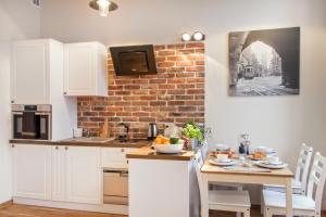 a kitchen with white cabinets and a brick wall at Gertrudy Old Town Apartments in Kraków
