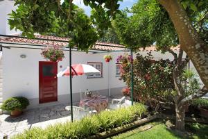a small white house with a table and an umbrella at Páteo da Várzea 2 in Colares