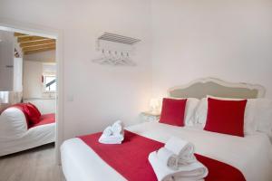 a white bedroom with red and white towels on a bed at Páteo da Várzea 2 in Colares