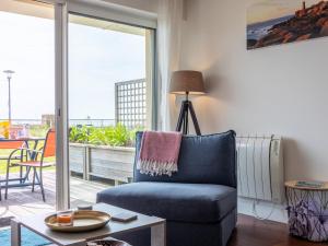 a living room with a blue chair and a balcony at Pieds Dans L'eau Madame est Servie in Trébeurden +13 photos