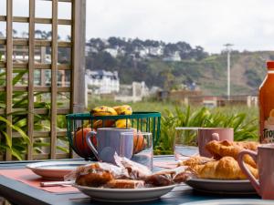 a table with plates of pastries and a basket of fruit at Pieds Dans L'eau Madame est Servie in Trébeurden