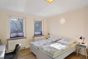 a white bedroom with a bed and two windows at Ferienhaus Berger 2025 in Bad Karlshafen
