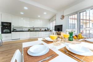a kitchen with white cabinets and a table with plates and wine glasses at Casa Ohana Fuengirola in Fuengirola