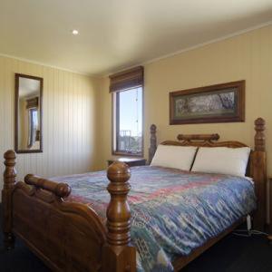 a bedroom with a large bed with a wooden frame at Camelot in Dinner Plain