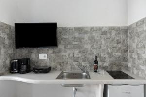 a kitchen with a sink and a tv on a wall at Politimis Studio N1 in Amorgos