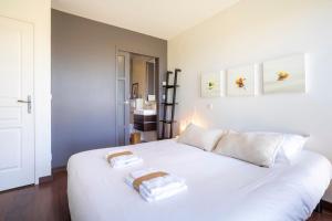 a bedroom with a white bed with two towels on it at Maison Horizon - 3 ch - 100m plage in Le Guilvinec
