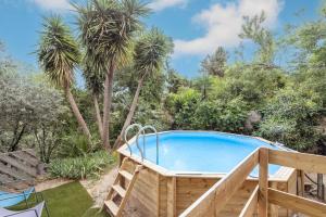 a pool in a garden with palm trees at Petite maison de bois in Banyuls-dels-Aspres