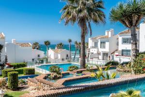 a view of the pool at a resort with palm trees at Rocas del Mar in Mijas