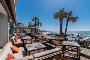 an outdoor patio with tables and chairs and the ocean at Rocas del Mar in Mijas