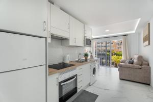 a kitchen with white cabinets and a sink and a dishwasher at Granada Park S01A in Arona