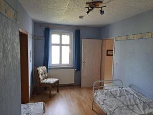 a room with a bed and a chair and a window at Hof Schumacher in Gumtow