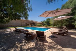 a swimming pool with two chairs and an umbrella at Cugulutx in Llucmajor