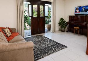 a living room with a couch and a piano at Costa Family-Casa Costa (downtown Santa Rita) in Santa Rita do Sapucaí
