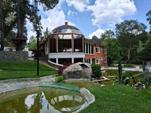 a house with a pond in front of a building at ASGARD RESORT GUATEMALA in Santiago Sacatepéquez