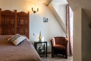 a bedroom with a bed and a chair at Demeure D'antan - Chambres d'hôtes in Beblenheim