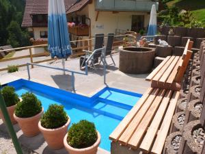 a pool with benches and umbrellas and potted plants at Paradies Im Schwarzwald in Bad Peterstal-Griesbach