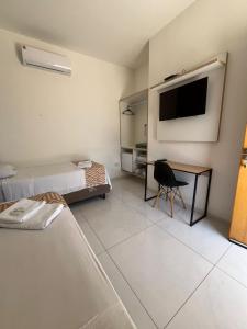 a room with two beds and a desk and a television at Modelo Prime Hotel in Ribas do Rio Pardo