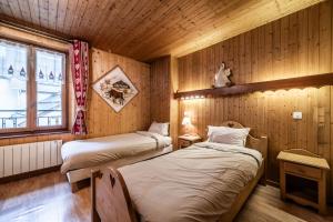 two beds in a room with wooden walls at L' Abbaye in Abondance
