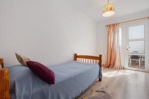 a bedroom with a bed with purple pillows and a window at Casa Tanai in El Cotillo