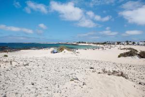 a beach with a lot of people in the water at Casa Tanai in El Cotillo