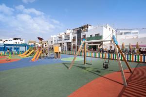 a playground with a slide and play equipment in front of a building at Casa Tanai in El Cotillo