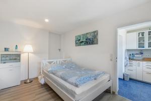 a white bedroom with a bed and a kitchen at Ferienwohnung Norma in Taunusstein