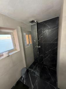 a bathroom with a shower with a black tile wall at Casa Mark in Forza dʼAgro
