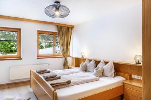 a bedroom with a bed with white sheets and pillows at Hotel Sonnblick - Wohnung Klaus in Kartitsch