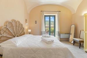 a bedroom with a large white bed and a window at Le Residenze In Piazza in Bosa