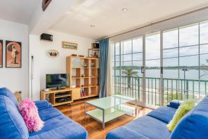 a living room with a blue couch and a large window at Casa Ullastre de Fornells in Fornells