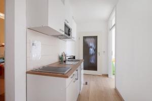 a white kitchen with a sink and a counter at Birkethof Gartenblick in Grimoldsried