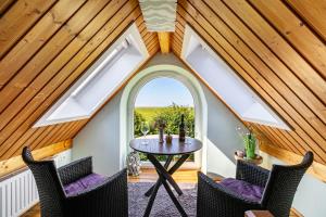 an attic room with a table and chairs and a window at Ferienwohnung Kiebitznest in Kaiser Wilhelm Koog