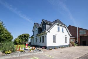 a white house with a black roof at Ferienwohnung Kiebitznest in Kaiser Wilhelm Koog
