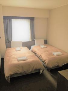 two beds in a room with a window at Hotel Crown Hills Yamagata in Yamagata