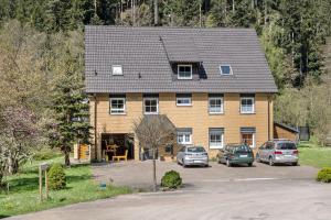 a large house with cars parked in front of it at Ferienwohnung am Waldrand in Alpirsbach