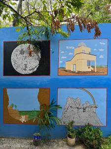 a wall with pictures of a house and a rock at Hostal Arambulo in Villavieja