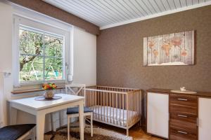 a nursery with a crib and a table and a window at Ferienwohnung am Waldrand in Alpirsbach