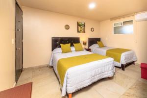 ein Schlafzimmer mit zwei Betten mit gelb-weißer Bettwäsche in der Unterkunft Hotel Boutique Las Campanas in Tlaxcala de Xicohténcatl
