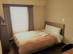 a hotel room with a bed with a window at Hotel Crown Hills Yamagata in Yamagata