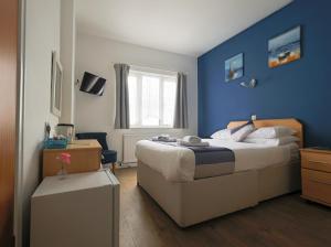 a bedroom with a large bed and a blue wall at De L'Etang in Saint Helier Jersey