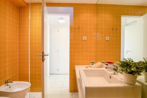 an orange tiled bathroom with a sink and a toilet at Modern Apartment by the Sea in Quarteira +15 photos