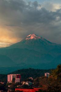 a snow covered mountain in the distance with a city at Hostal Santa Anna in Xalapa