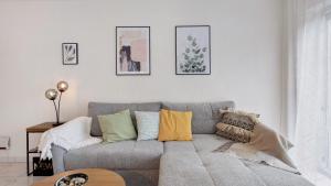 a living room with a gray couch with colorful pillows at Ferienwohnung Heidegarten in Radolfzell am Bodensee