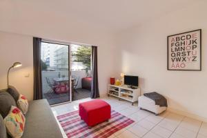 a living room with a couch and a red stool at Modern Apartment by the Sea in Quarteira